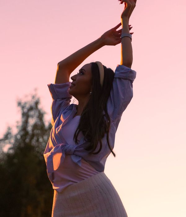 Woman in a graceful yoga pose with coral light accents.